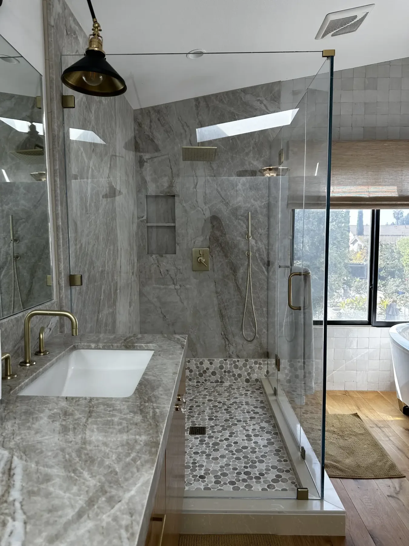 Marble bathroom with frameless glass shower and skylight