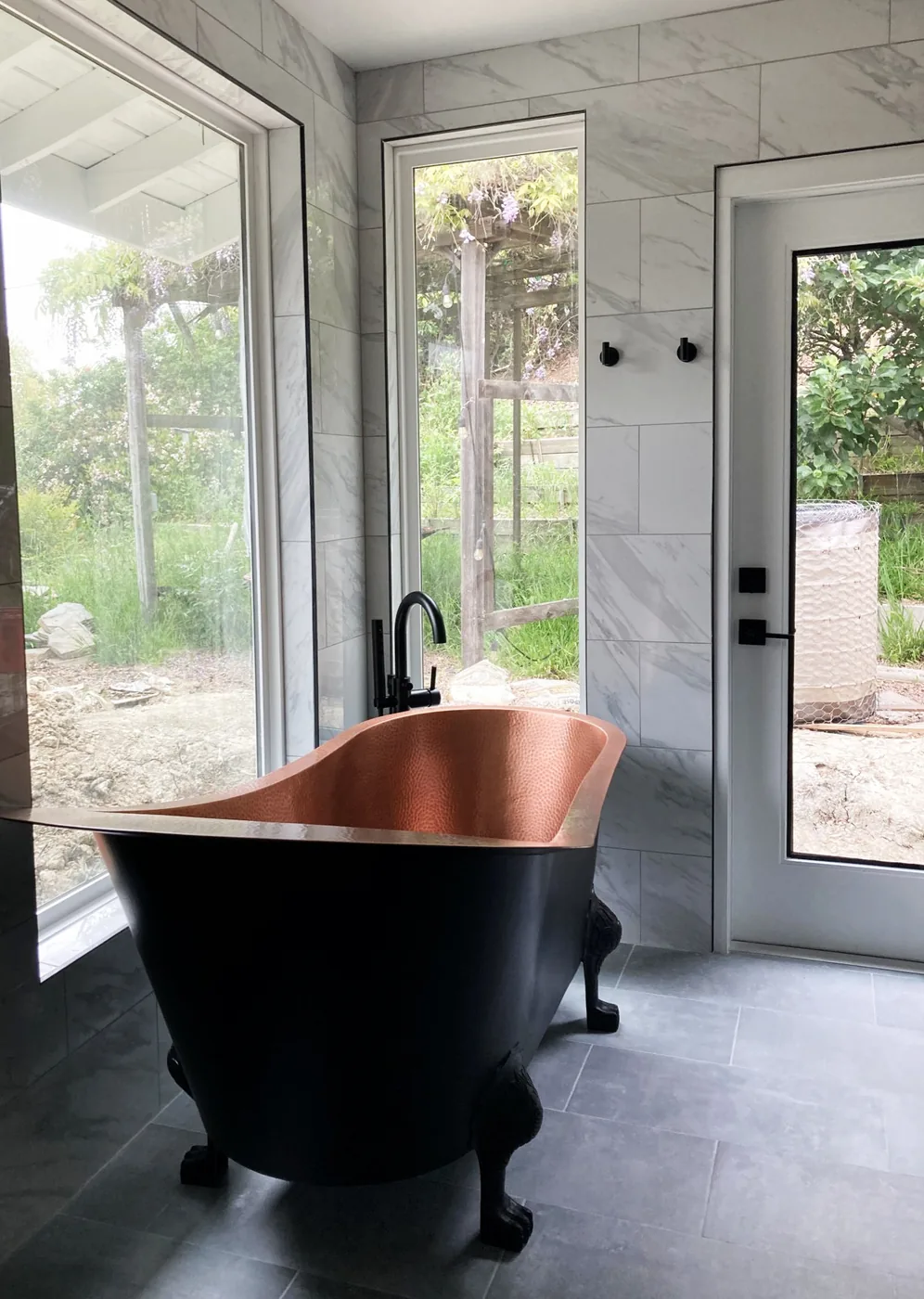Copper clawfoot tub with marble surround and garden view