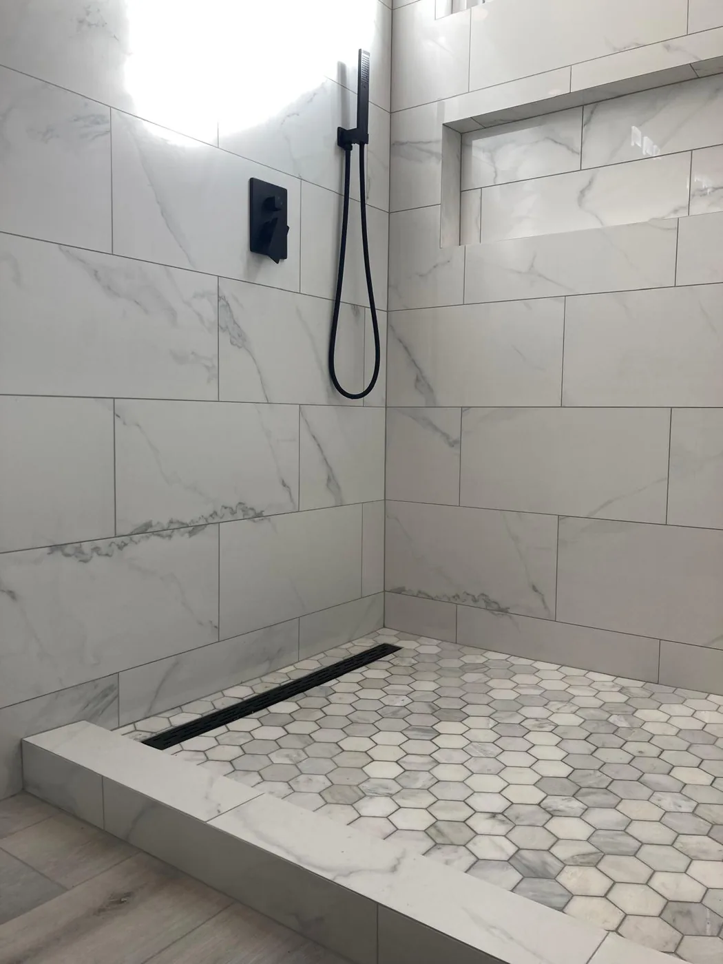 Marble walk-in shower with hex-tile floor and linear drain